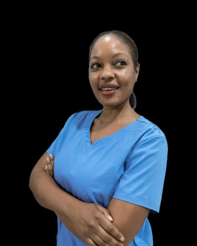 A home care aide in blue work clothes, arms folded, smiling